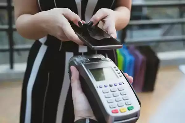 Woman using her mobile phone to pay for goods.