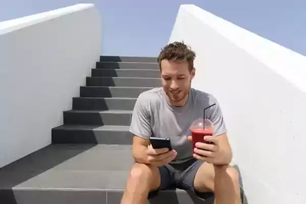 Man sitting on stairs outside looking at his mobile phone.