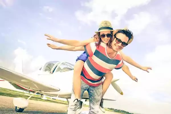 Young couple standing in front of a small airplane.