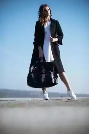 Woman modeling long coat and purse.