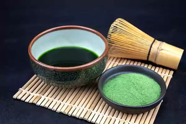 Placemat with a bowl of liquid and a bowl of green powder.