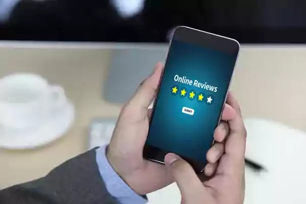 Person holding a mobile phone with online reviews displayed on the screen.