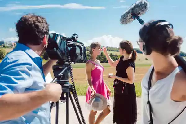 Film crew shooting a woman outside.