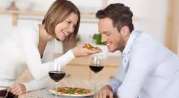 Couple drinking red wine with pizza.