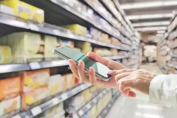 Person looking on mobile phone while in grocery store.