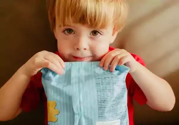 Child holding a bag of snacks.