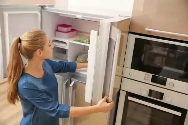 Woman placing food in a refrigerator.