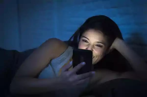 woman using phone in bed