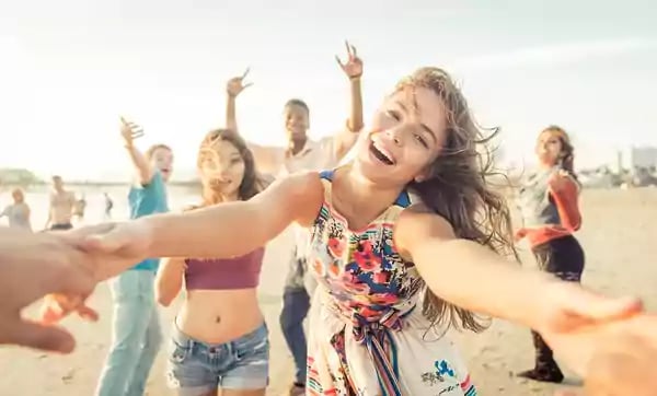 Group of young adults at the beach smiling.