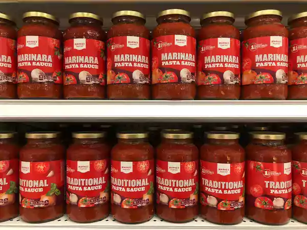 Two shelves filled with marinara pasta sauce jars.
