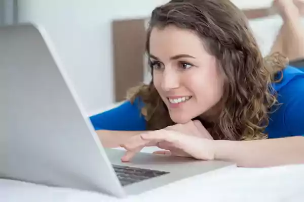 Woman lying down looking at her laptop computer.