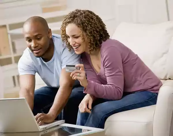 Couple sitting on a couple with a credit card making a purchase online.