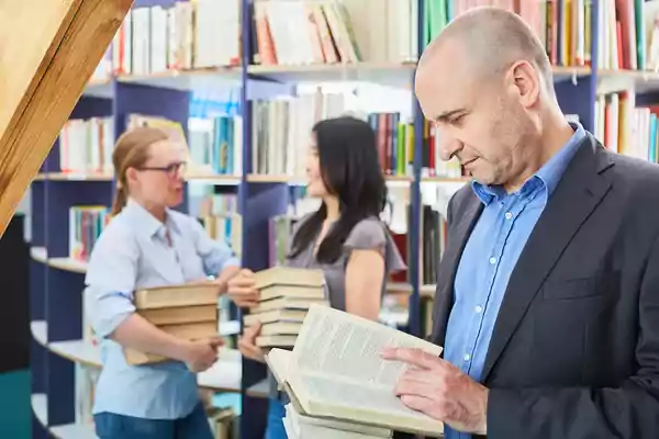 Group of people in a library reading books.