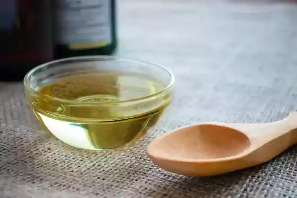 MCT oil in a small glass bowl with a wooden spoon nearby.